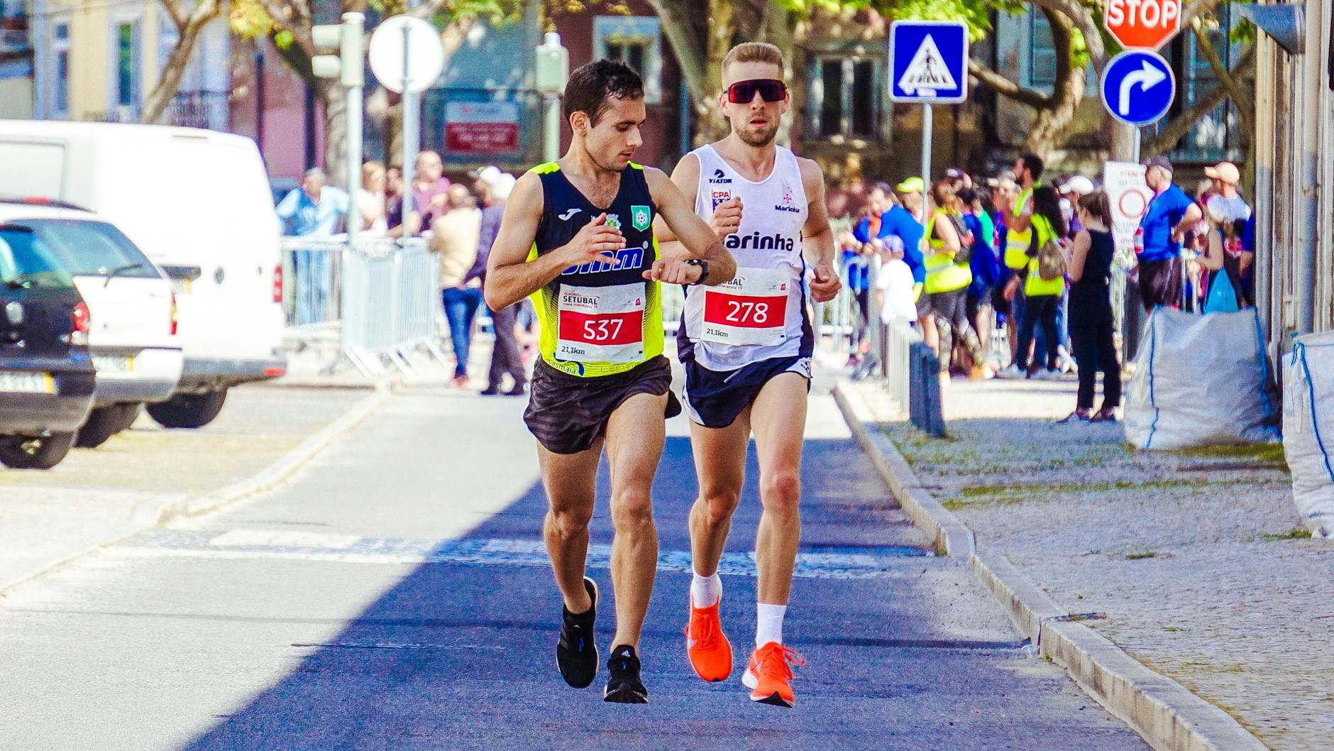 Dwóch biegaczy rywalizuje w miejskim maratonie w pełnym słońcu