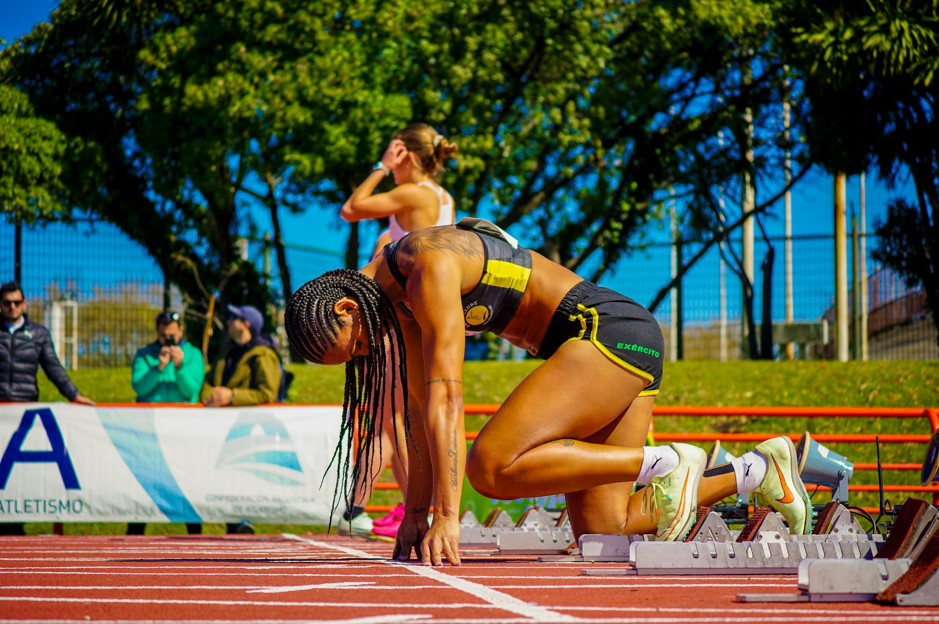 Sprinterka w pozycji startowej na bieżni przed biegiem na 60–100 m