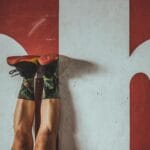 Osoba w kolorowych skarpetkach ćwicząca przy czerwonej ścianie