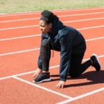 Sprinterka w pozycji startowej na bieżni lekkoatletycznej w słońcu