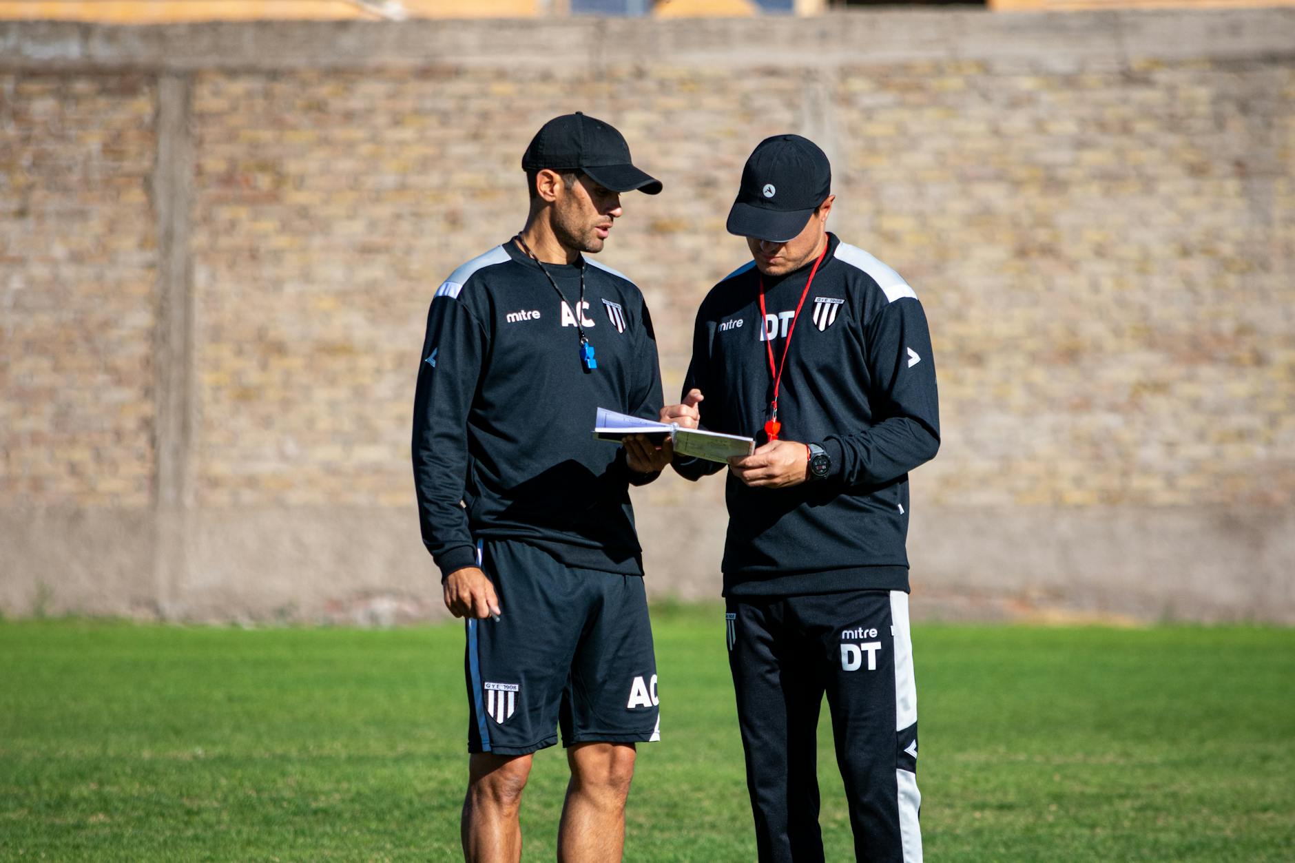 Dwóch trenerów piłki nożnej omawia taktykę na boisku