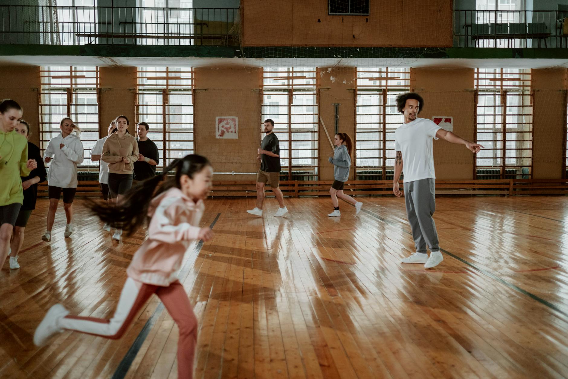 Dzieci w różnym wieku biegnące razem na krytej sali sportowej