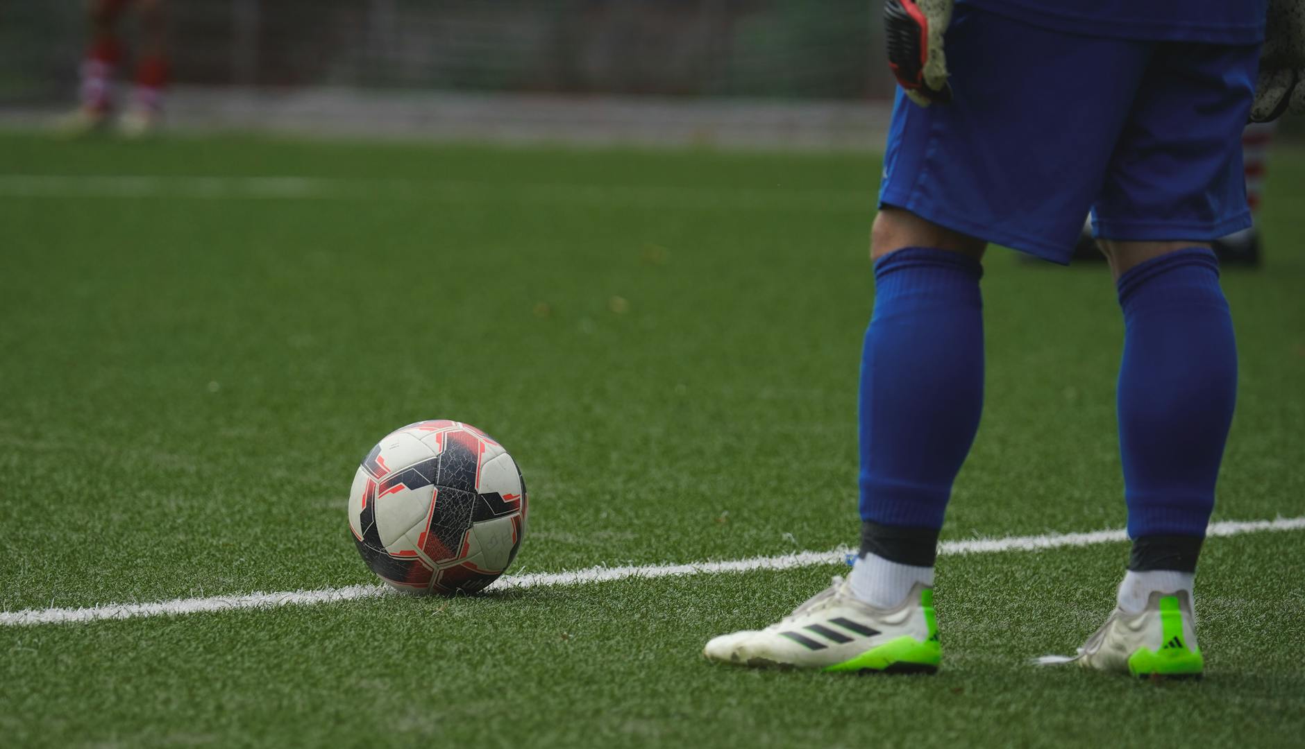 Piłkarz przy piłce na murawie, przygotowujący się do stałego fragmentu