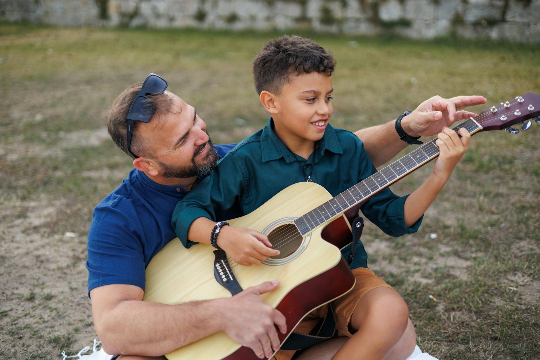Ojciec uczy syna grać na gitarze na łonie natury