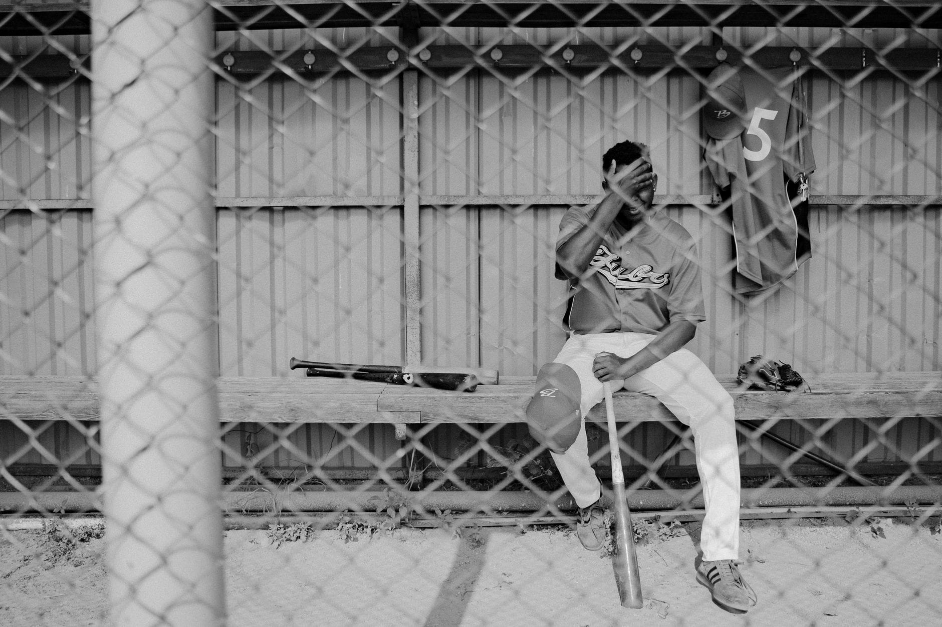 Smutny baseballista siedzący samotnie w dugoucie po porażce