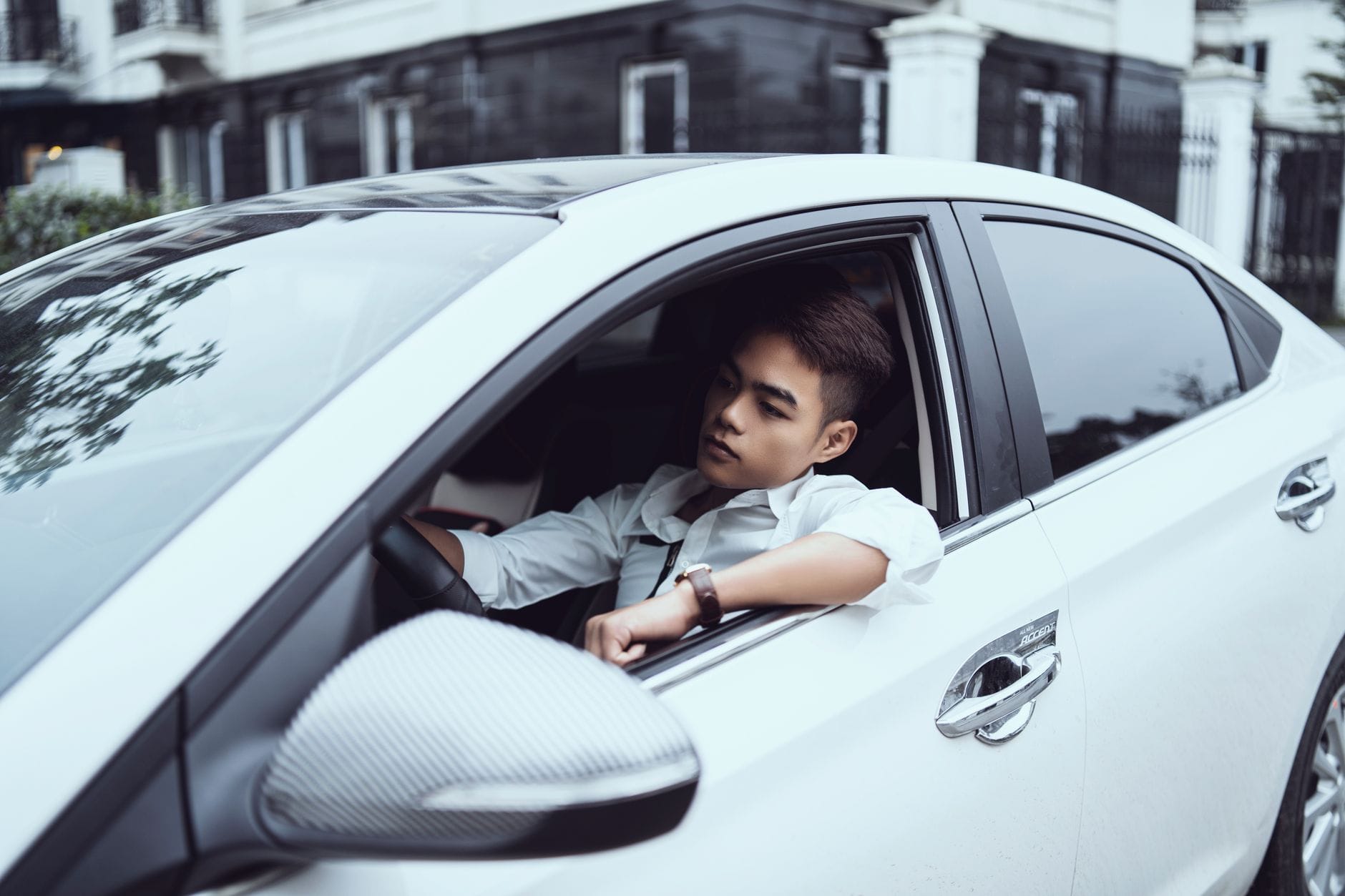 Pewny siebie młody kierowca prowadzi auto ulicą w centrum miasta